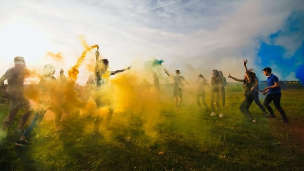 Happy friends girls waving colorful smoke at sunset