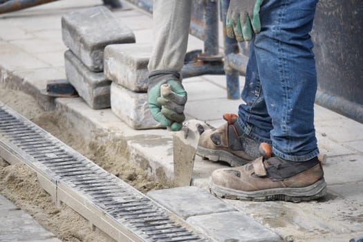 Skilled worker arranging bricks on a construction site pavement