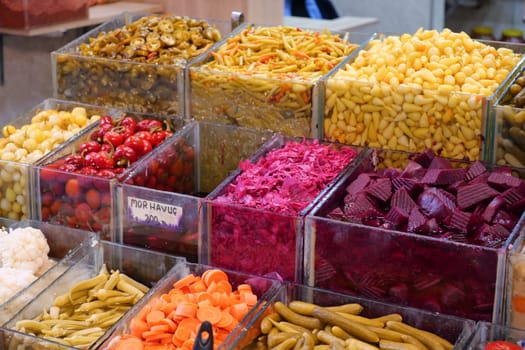 Vibrant array of pickled vegetables and fresh produce at local market.