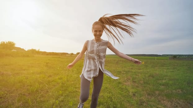 A girl with long hair amusingly runs around the field showing off her long hair