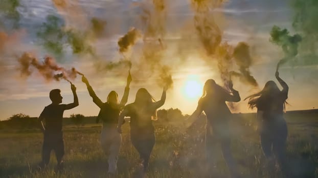 Happy friends waving colorful smoke at sunset