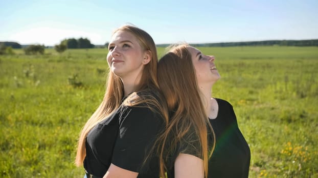 Portrait of two twin sisters in the field on a warm summer day.