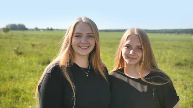 Portrait of two twin sisters in the field on a warm summer day.
