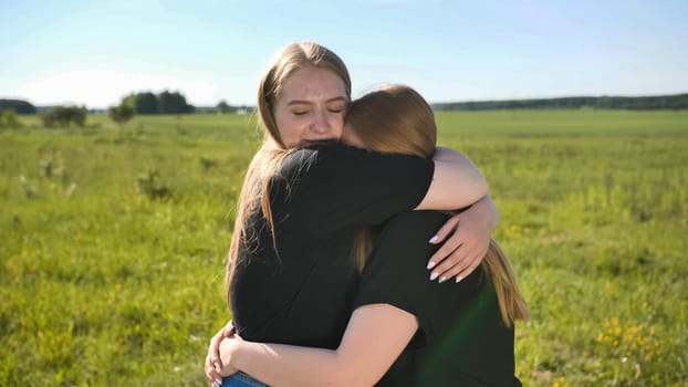 Portrait of hugging two twin sisters in the field on a warm summer day.