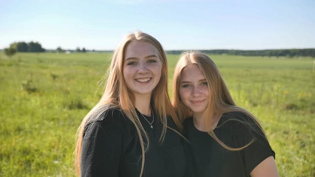 Portrait of two twin sisters in the field on a warm summer day.