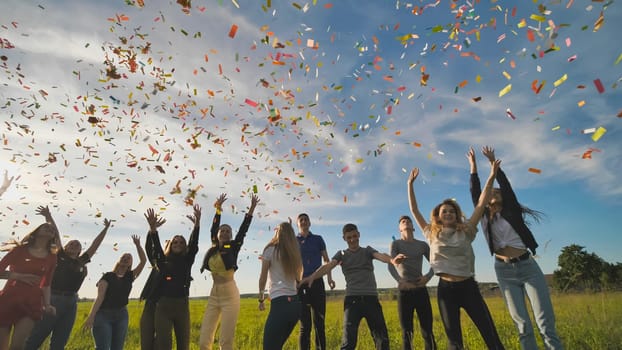 A group of friendly friends toss up candy at sunset in a field