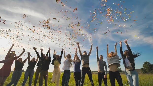 A group of friendly friends toss up candy at sunset in a field