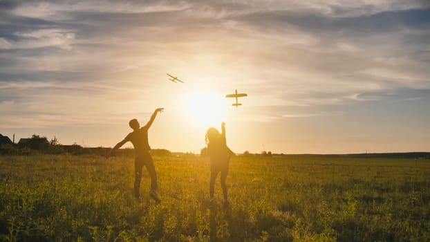 A guy and a girl launch a paralon plane at sunset