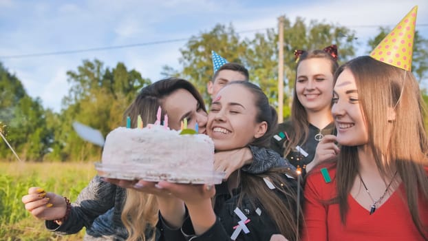 Happy friends celebrate their girlfriend's birthday. The birthday girl blows out the candles