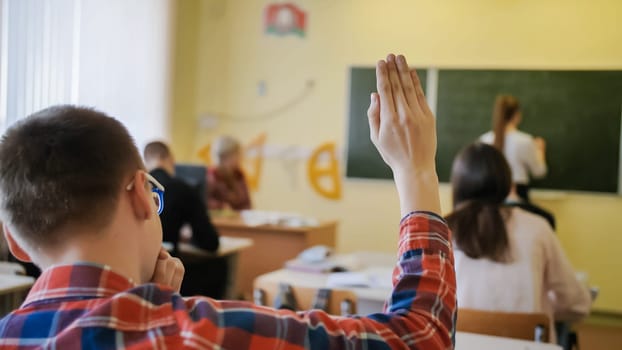 High school student raises his hand during the lesson