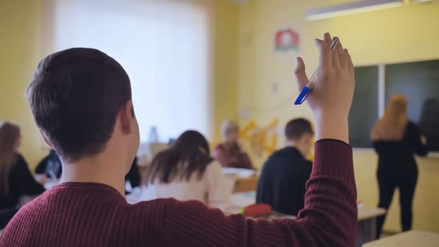 High school student raises his hand during the lesson