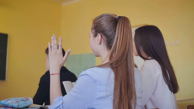 Schoolgirl raises her hand during the lesson