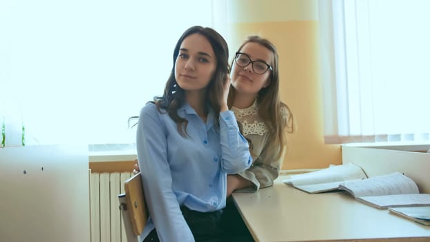 Two schoolgirls are smiling between lessons at their school