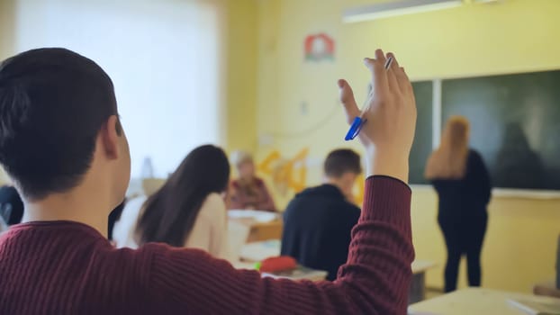 High school student raises his hand during the lesson