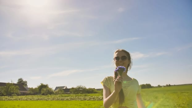 Young 17 year old girl with a cornflower flower outside the city on a summer day