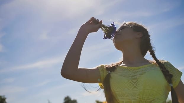 Young 17 year old girl with a cornflower flower outside the city on a summer day