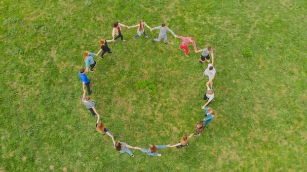 Friends in a circle holding hands make a round dance in the field