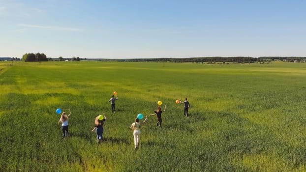 Friends walks across the field with colorful balloons