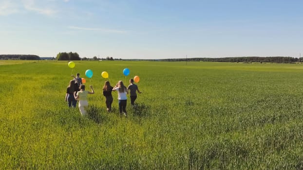 Friends walks across the field with colorful balloons