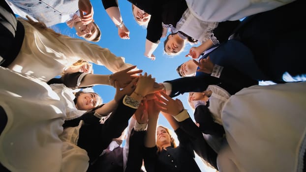 Happy friends graduates join hands together. The concept of a friendly team