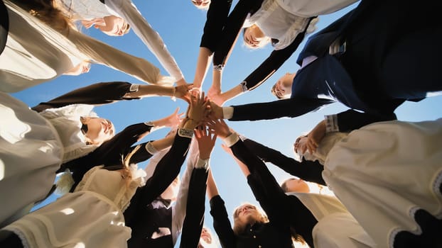 Happy friends graduates join hands together. The concept of a friendly team