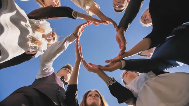 A group of graduate students make a circle from the palms of their hands