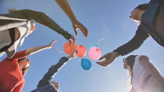 A group of friends release colorful balloons into the sky