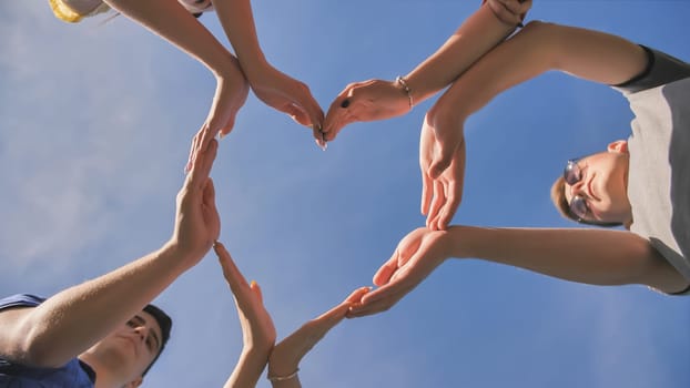 A group of friends makes a heart shape out of their hands