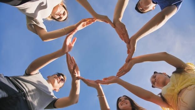 A group of friends makes a circle from the palms of their hands