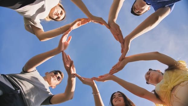 A group of friends makes a circle from the palms of their hands