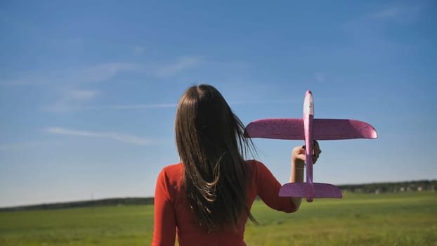 A girl launches a toy paralon airplane into the sky