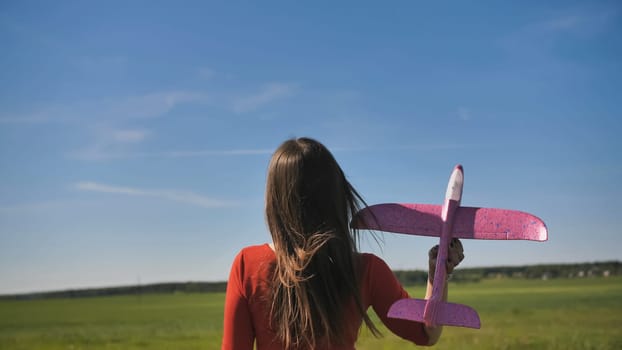 A girl launches a toy paralon airplane into the sky