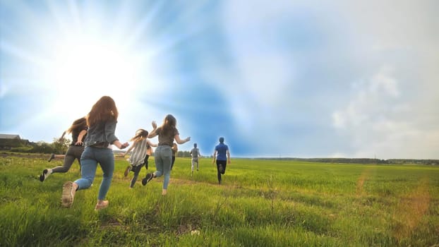 Happy friends run against the backdrop of a beautiful sky and sun