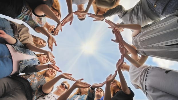 A large group of students makes a circle out of their hands