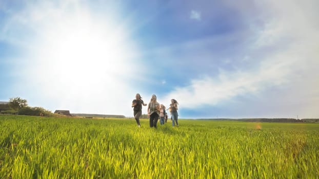 Happy friends run against the backdrop of a beautiful sky and sun