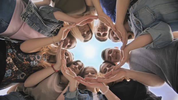 A large group of students makes a circle out of their hands