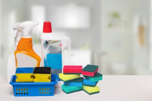 Household cleanliness and hygiene. Close-up of house cleaning products and cleaning supplies on a white table over abstract blurred bath background. Household chore concept. Copy space.