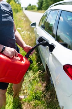 Force majeure, problems on the road, self-refuelling. The driver fills up the empty tank of the car from a red canister on the side of the road