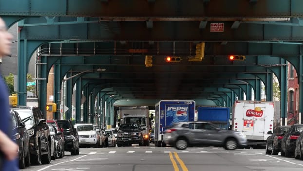 New York City, United States - 31 Aug 2023: Pepsi truck, elevated subway above street. Metropolitan bridge over road, Queens. Long Island metro line. Cars under metallic railway track. NYC urban life.
