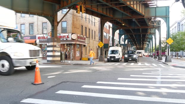 New York City, United States - 31 Aug 2023: Elevated subway above street. Metropolitan bridge over road, Queens. Long Island metro line, Court Square. Cars under metallic railway track. NYC urban life