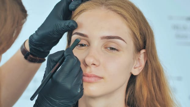 Permanent makeup. Permanent tattooing of eyebrows. Cosmetologist applying permanent make up on eyebrows - eyebrow tattoo