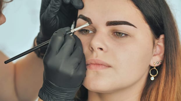 Permanent makeup. Permanent tattooing of eyebrows. Cosmetologist applying permanent make up on eyebrows - eyebrow tattoo