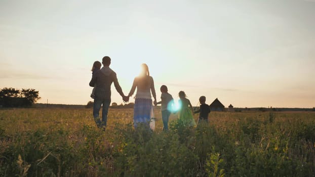 A large family walks along the field at sunset