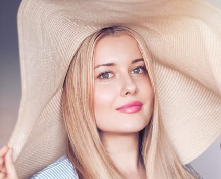 Woman, fashion and summer country charm, blonde beauty and elegance in wide brimmed beach hat. Feminine allure, timeless style and graceful glow. Smile, straw hat and blue striped blouse, natural lighting and effortless charm, fashion look idea