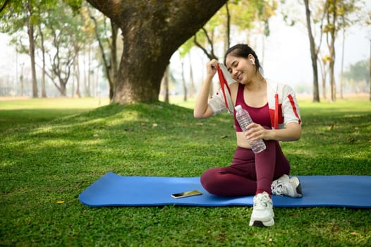 Young woman wiping sweat from her face cooling down after outdoor workout.
