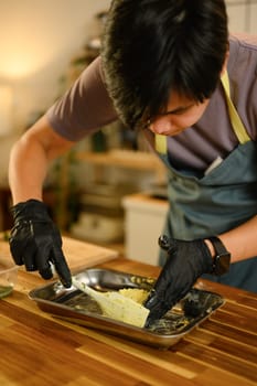 Shaping homemade compound butter with fresh herbs in a stainless steel tray.