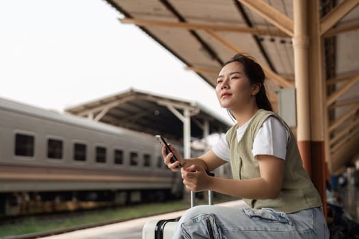 A thoughtful traveler takes a moment to reflect while using her smartphone at the train station, capturing the essence of journey preparation.