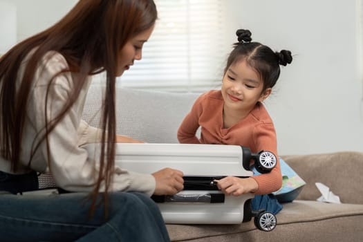 A joyful scene of a mother helping her daughter pack clothes and essentials into a suitcase, highlighting the excitement of travel and family time.