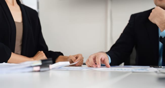 The hands of team members work together to review detailed reports and charts, showcasing the collaborative effort involved in data-driven business decisions.