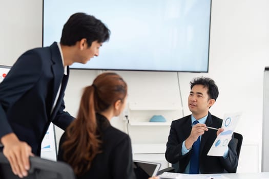 Three colleagues are discussing project data and sharing insights in a modern office environment, showcasing teamwork and communication.